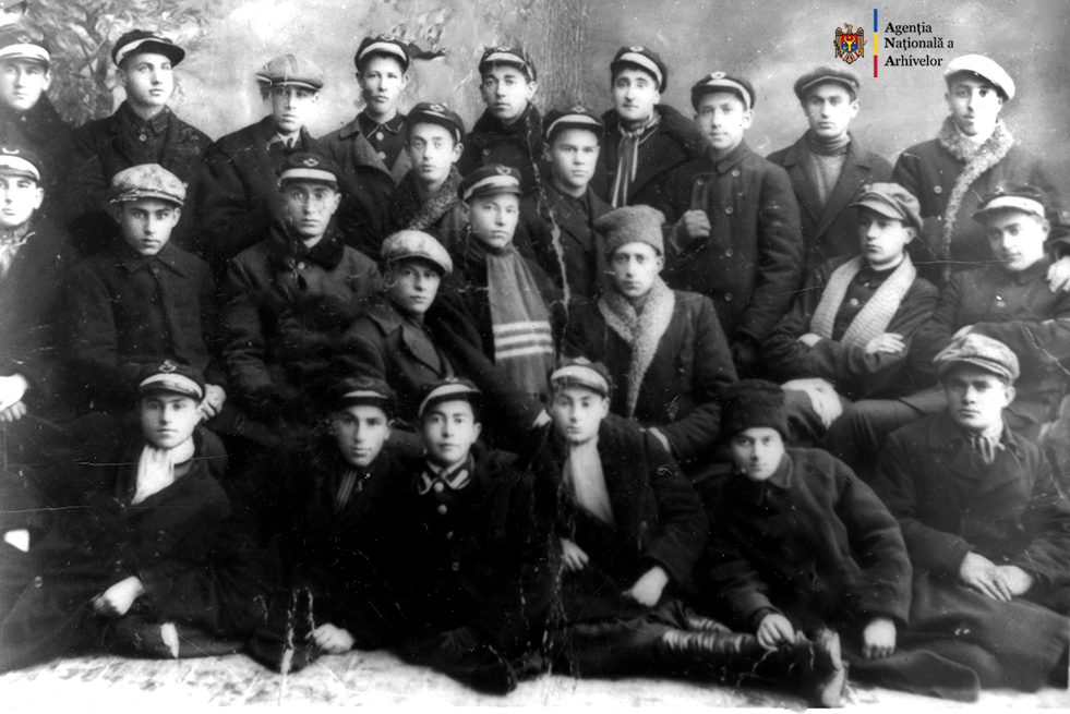 Un grup de elevi ai Şcolii Reale „Ştefan cel Mare” din or. Tighina. În rândul al treilea, al şaptelea din stânga, Valentin Mednec, anul 1927. ANA, fototeca, c. a. 21/221.