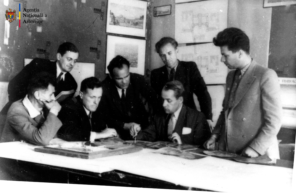 Un grup de arhitecţi implicaţi în reconstrucţia oraşului Chişinău, în timpul lucrului. Al patrulea din stânga, Valentin Mednec, or. Chişinău, anul 1947. ANA, fototeca, c. a. 21/229.